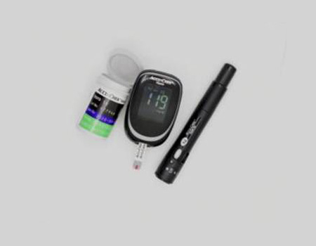 Blood glucose meter, pen, and pill bottle arranged on a surface.