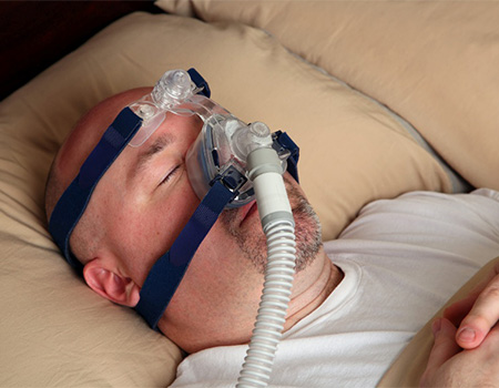 A man lying in bed with a breathing mask on.