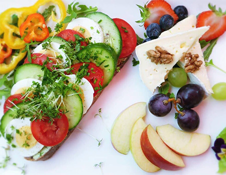 A plate with an assortment of sliced fruit, cheese, and eggs